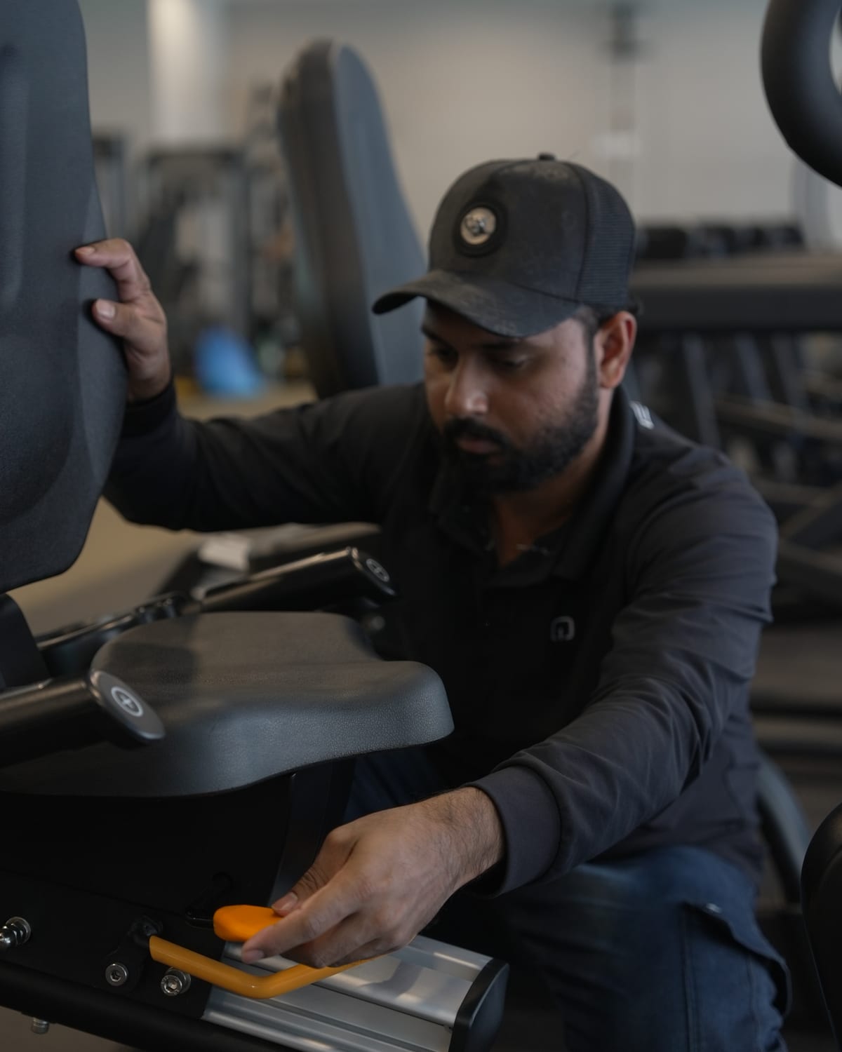 An Equipt engineer adjusting a seat carriage on a cross-trainer.