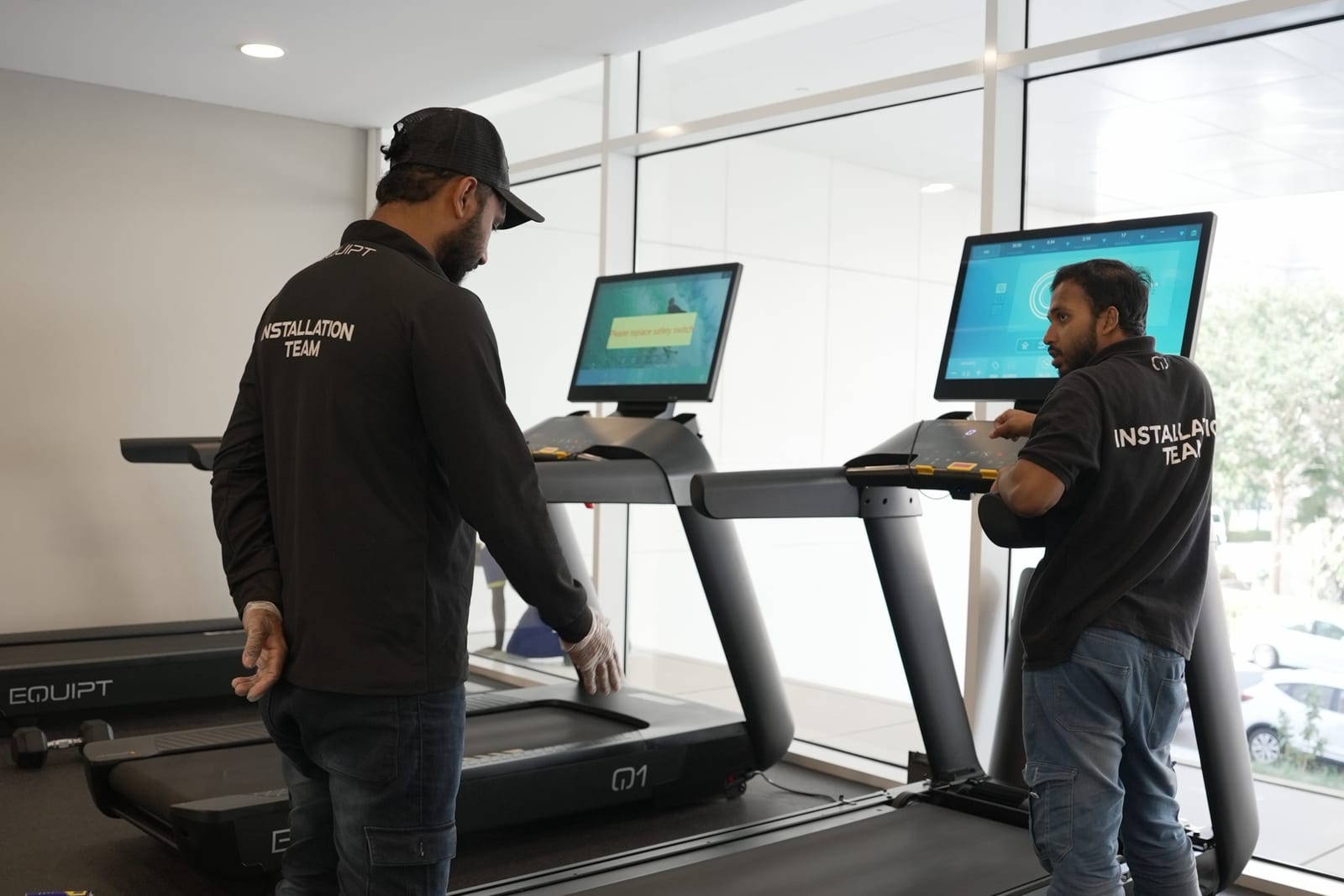 Two Equipt engineers commissioning a pair of treadmills.